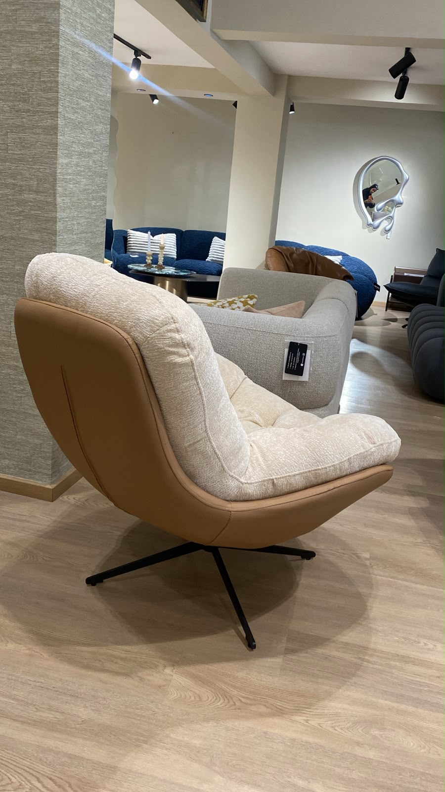 Bergère contemporaine avec assise moelleuse, dossier enveloppant et piètement pivotant en métal, idéale pour un salon moderne.