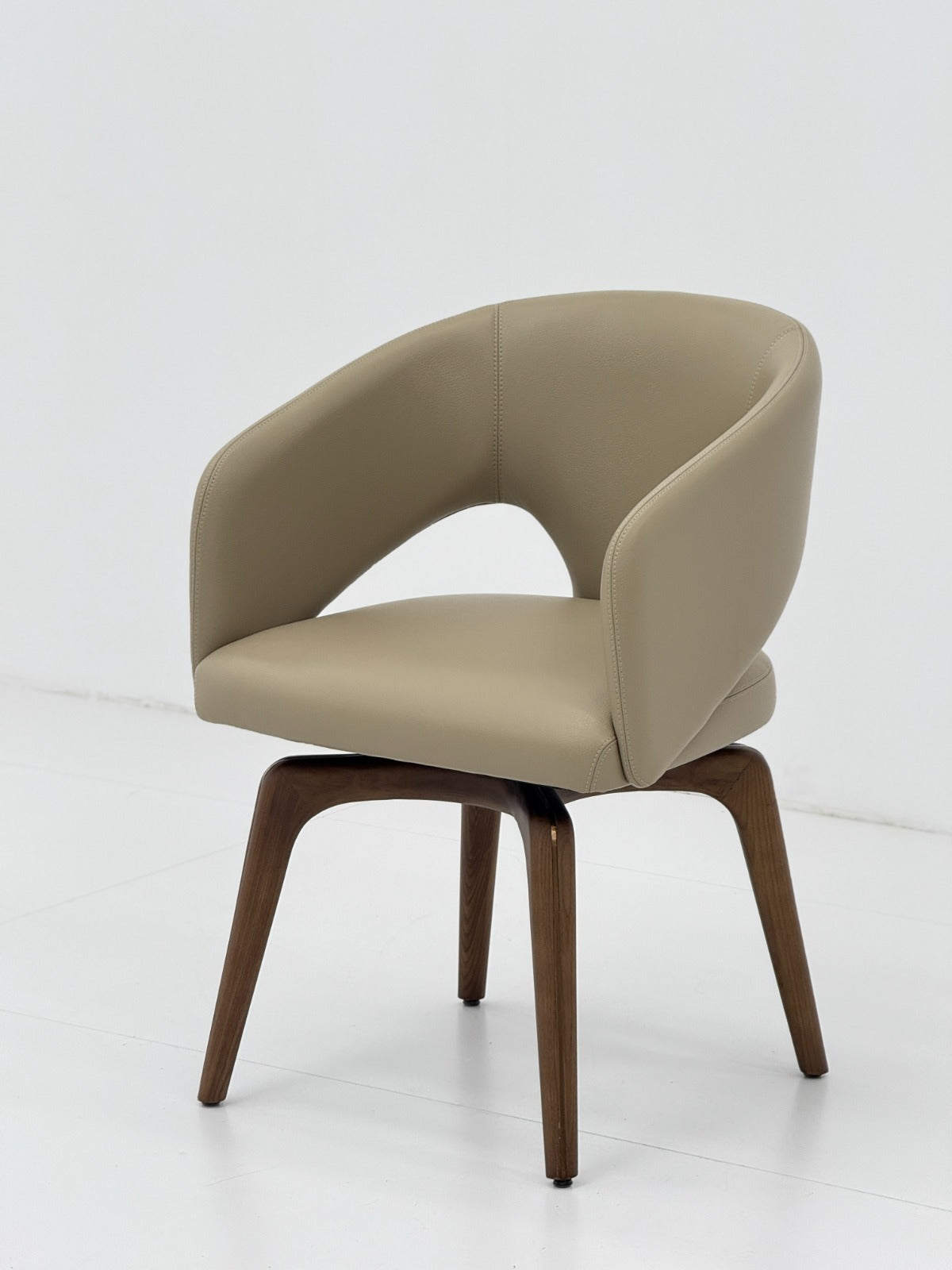 Chaise contemporaine avec assise rembourrée, dossier enveloppant et piètement en bois, idéale pour une salle à manger moderne.